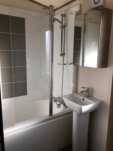a white bathroom with a sink and a shower at Ballies Retreat in Lossiemouth