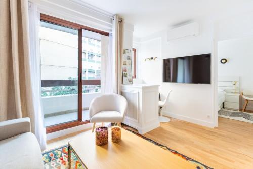 - un salon avec une chaise blanche et une grande fenêtre dans l'établissement Passy Trocadéro Chic, à Paris