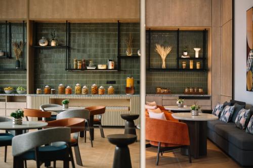 a restaurant with tables and chairs and a couch at Iconic Marjorie Hotel, Penang, a Tribute Portfolio Hotel in Bayan Lepas