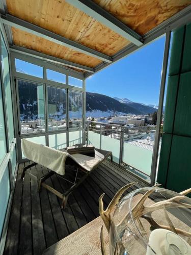 - une terrasse couverte avec une chaise et une table offrant une vue dans l'établissement Davos Luxury Apartment - 5 Min walking to Congress Center, à Davos