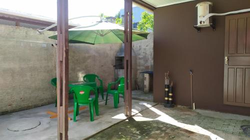 a green table and chairs under an umbrella at Res Canto dos Pássaros - Chalé 03 in Rio Grande