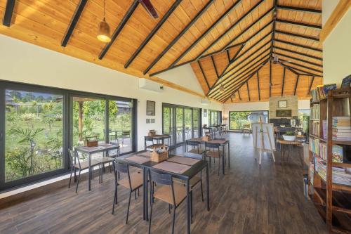 een kamer met tafels, stoelen en ramen bij Echor Hill Farm Cottages Palampur in Pālampur