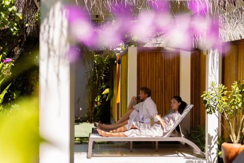 a man and a woman sitting on a chair at OBLU NATURE Helengeli-All-Inclusive with free Transfers in North Male Atoll