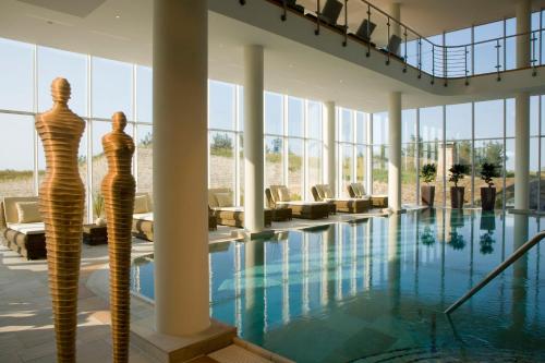 un hall avec une piscine et des chaises dans l'établissement Strandhotel Dünenmeer - Adults only, à Dierhagen