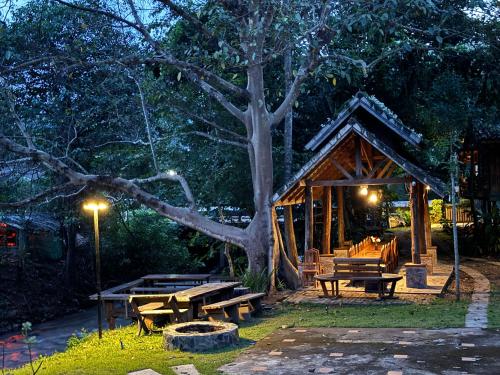 a wooden pavilion with picnic tables and a tree at Ban Kaew Mo Ra Glamping & Restaurant in Pang Mapha