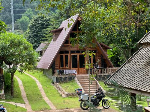 a house with a motorcycle parked in front of it at Ban Kaew Mo Ra Glamping & Restaurant in Pang Mapha