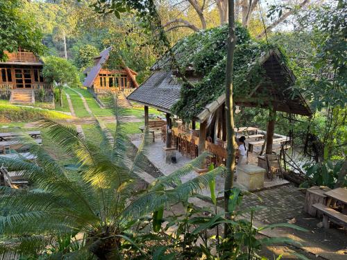 a small building with a green roof in a forest at Ban Kaew Mo Ra Glamping & Restaurant in Pang Mapha