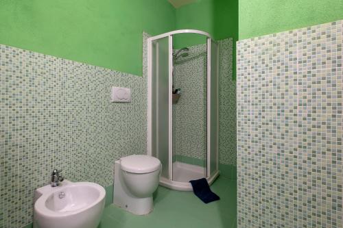 a green bathroom with a toilet and a sink at Rifugio Costiero in Cascabraga