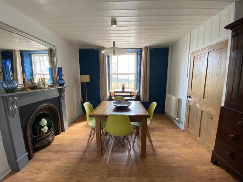 a dining room with a table and chairs and a fireplace at Secluded farmhouse with views in Cwrt-newydd