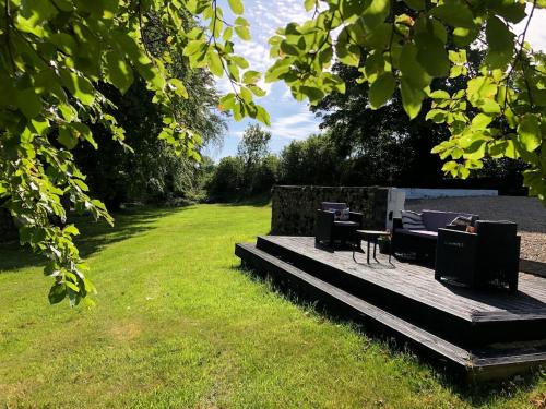 a wooden deck with chairs and a table in a field at Secluded farmhouse with views in Cwrt-newydd