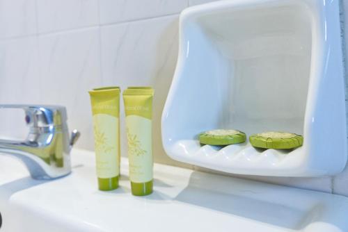 two green toothbrushes in a container on a bathroom sink at Zografia in Corfu