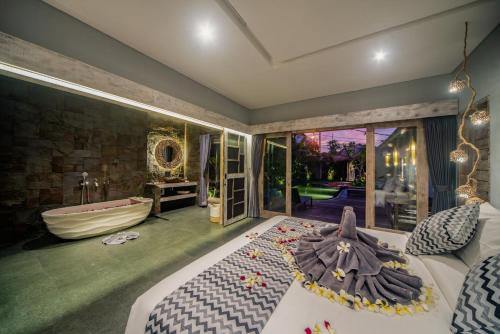 a master bedroom with a tub and a bed with a robe at Luxury-Sang Villa- Central Sanur in Sanur