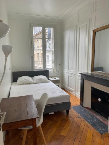 une chambre blanche avec un lit et une cheminée dans l'établissement Appartement Hypercentre vue Cathédrale, à Rouen