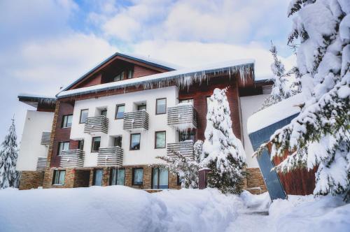 a large building with snow on the side of it at Euphoria Club Hotel in Borovets