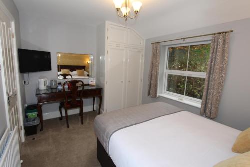 a bedroom with a bed and a desk and a window at Fern Howe Guest House in Keswick