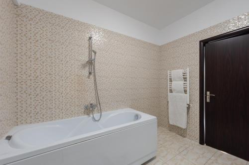 a bathroom with a white bath tub in a room at Luxury Apartment in Râmnicu Vâlcea