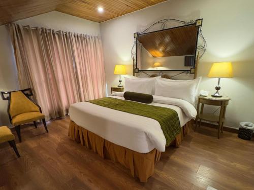 a hotel room with a large bed and two lamps at Maisonette Firhill Hotel & Resort in Murree