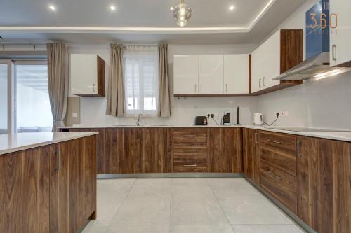 a kitchen with wooden cabinets and white appliances at Fully equipped 2BR home with Pool & Gym access by 360 Estates in St. Paul's Bay