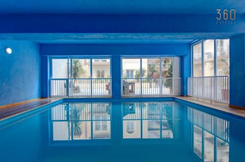 a swimming pool with blue walls and windows at Fully equipped 2BR home with Pool & Gym access by 360 Estates in St. Paul's Bay