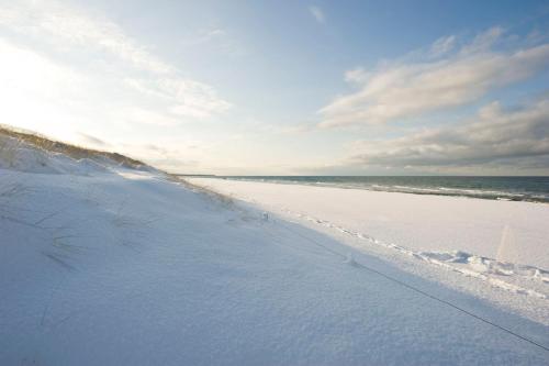 a beach covered in snow with the ocean in the background at Strandhotel Dünenmeer - Adults only in Dierhagen