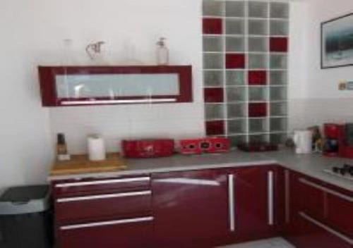 une cuisine avec des carreaux rouges et blancs sur le mur dans l'établissement En ville un coin de campagne, au Cannet