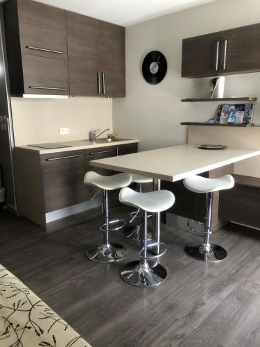 - une cuisine avec une table et des tabourets de bar dans l'établissement Aux Angles superbe studio refait à neuf et très bien équipé, aux Angles