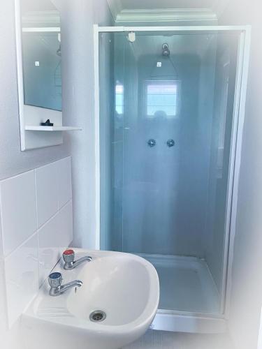 a white bathroom with a sink and a shower at Gecko Accommodation in Hotazel
