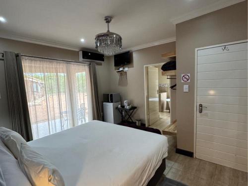 a bedroom with a large white bed and a window at Thabazimbi Country Lodge in Thabazimbi