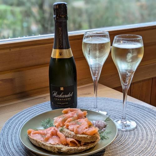 a bottle of wine and a plate of food and two glasses at Roulotte Ravel-Emoi Chambre Insolite de Charme in Ramillies
