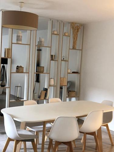 une salle à manger avec une table et des chaises blanches dans l'établissement Maison au coeur du village, à Eyragues