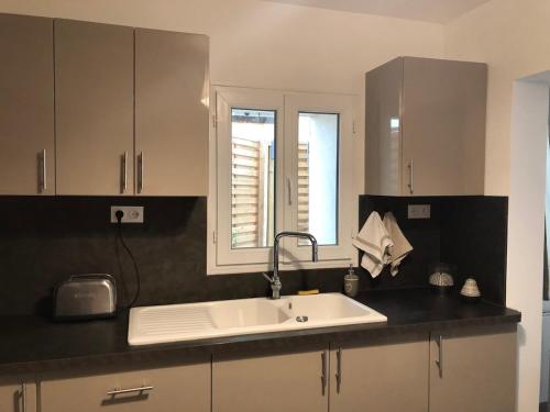 une cuisine avec un évier blanc et une fenêtre dans l'établissement Maison au coeur du village, à Eyragues