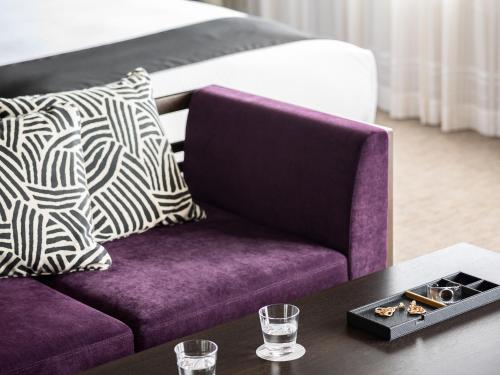 a purple couch and a table in a room with a bed at Mitsui Garden Hotel Kyobashi - Tokyo Station in Tokyo