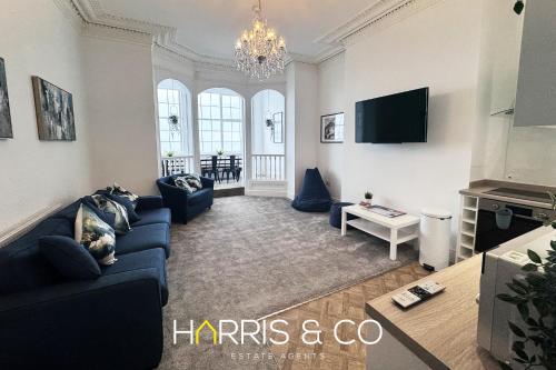 a living room with a blue couch and a tv at New Sandpiper Apartments in Fleetwood