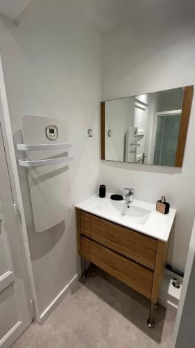 une salle de bain avec un lavabo et un miroir dans l'établissement L 'Escale Amicale, au Mans