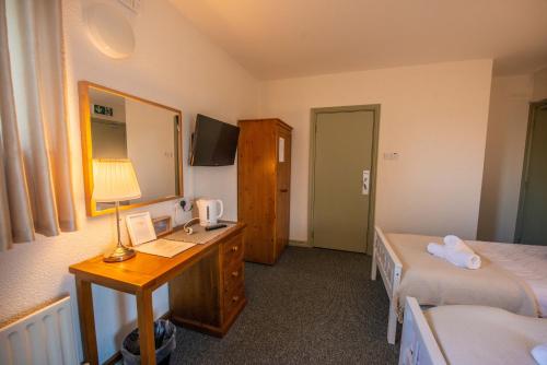 a hotel room with a desk and a bed and a bedroom at Greenfield Lodge Hotel Bar & Bistro in Headford
