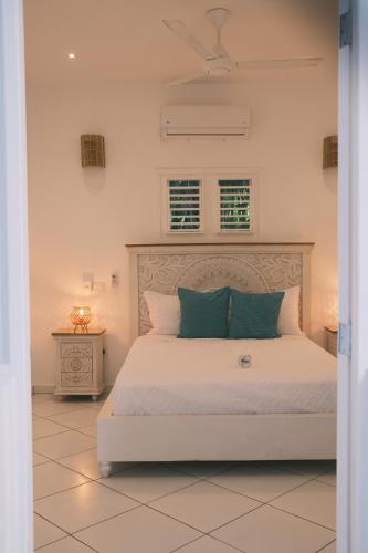 a bedroom with a large white bed with blue pillows at El Mosquito Boutique Hotel Playa Bonita in Las Terrenas