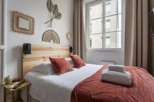 une chambre avec un lit avec des oreillers rouges et une fenêtre dans l'établissement SmartStay Bon Pasteur- Croix rousse, à Lyon