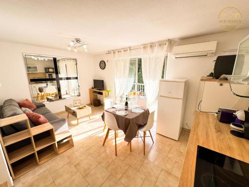 a living room with a table and a refrigerator at L'échappée verte - T2 - Confort -Piscine - Tennis- Parking - Climatisation - SudSéjourConciergerie in Canet-en-Roussillon