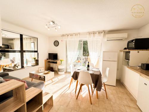 a kitchen and living room with a table and chairs at L'échappée verte - T2 - Confort -Piscine - Tennis- Parking - Climatisation - SudSéjourConciergerie in Canet-en-Roussillon