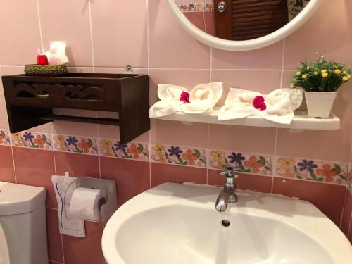 a bathroom with a sink and a mirror and a toilet at Naraya Homestay in San Pa Tong