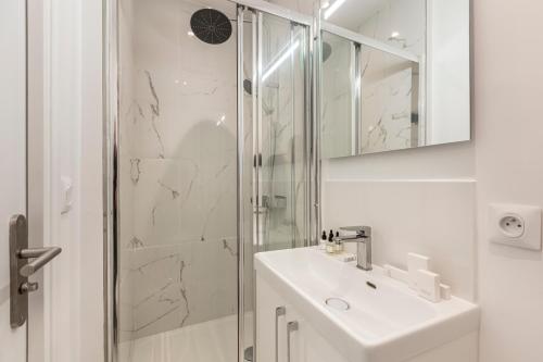 une salle de bain blanche avec un lavabo et une douche dans l'établissement Sweett - Batignolles, à Paris