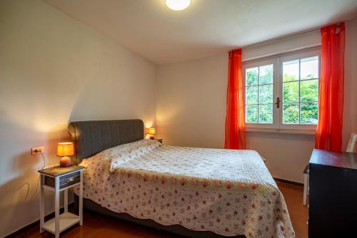 a bedroom with a bed and a window with red curtains at Casa Sabine, appartamento con giardino e vista Rocca in Vesta