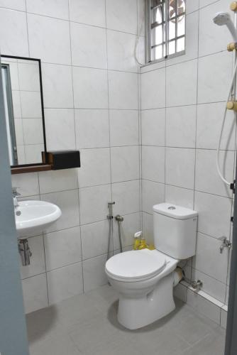 a white bathroom with a toilet and a sink at Rain Tree Homestay in Bintulu