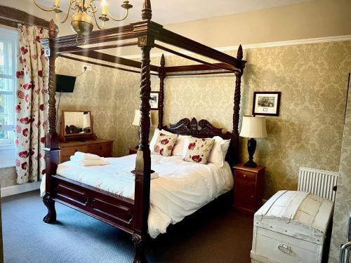 a bedroom with a canopy bed with white sheets and pillows at Old Hall Hotel Hope in Hope