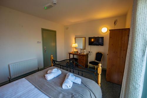 a bedroom with a bed with two towels on it at Greenfield Lodge Hotel Bar & Bistro in Headford