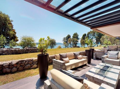 an outdoor patio with couches and a stone wall at Casa en la Nueva Puntilla in Villarrica