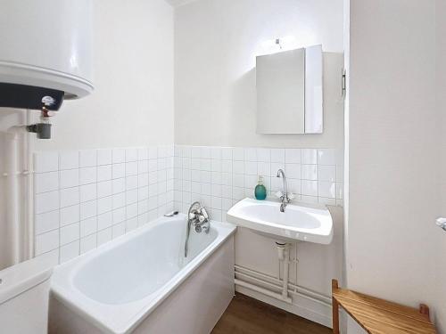 une salle de bain blanche avec une baignoire et un lavabo dans l'établissement Appartement rénové 5 pers. avec parking, à 100m plage, centre Merville-Franceville, expo Sud - FR-1-465-71, à Merville-Franceville-Plage