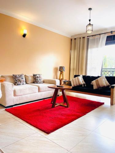 a living room with two couches and a red rug at Rafah Apartment in Namugongo