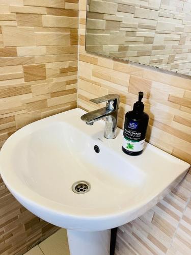 a bathroom sink with a bottle of soap on it at Rafah Apartment in Namugongo