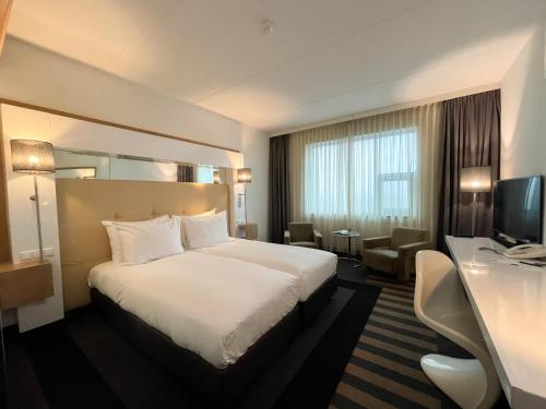 ein Hotelzimmer mit einem weißen Bett und einem Schreibtisch in der Unterkunft WestCord WTC Hotel Leeuwarden in Leeuwarden